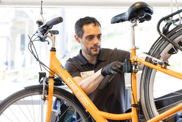 Un technicien répare une roue de vélo à l'atelier de la Maison du vélo